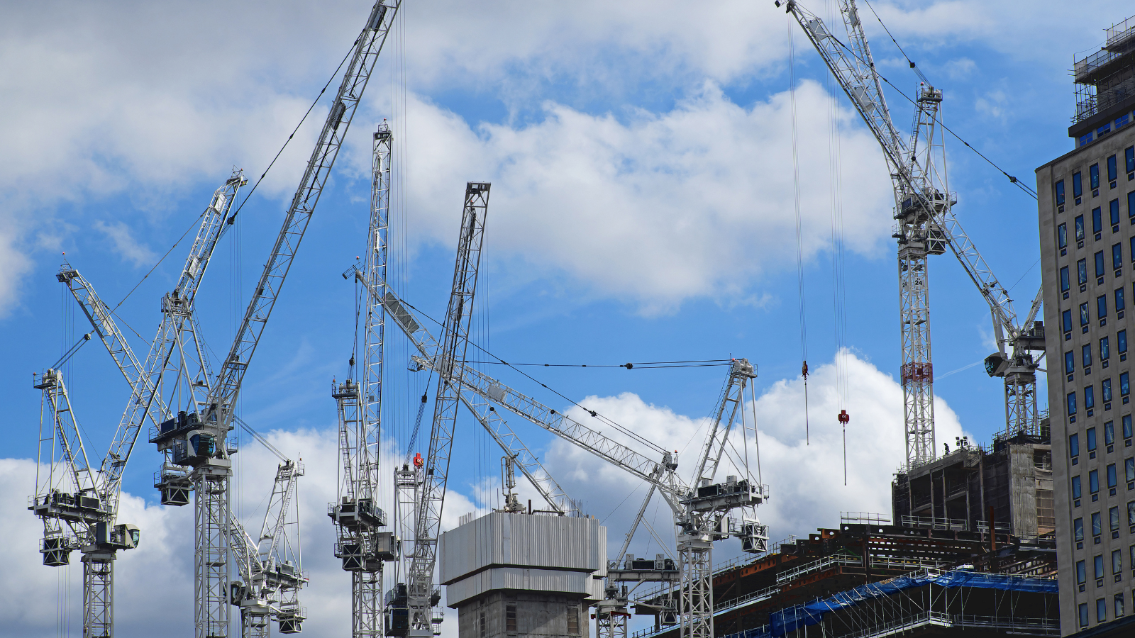 Image of fleet of cranes on a UK construction site with blue skies.