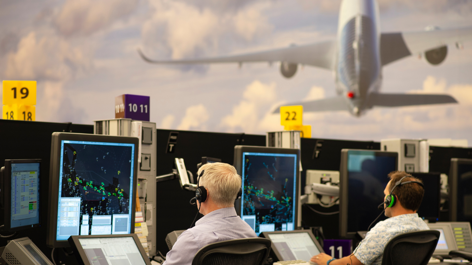 Two male air traffic controllers at Swanwick with plane in background