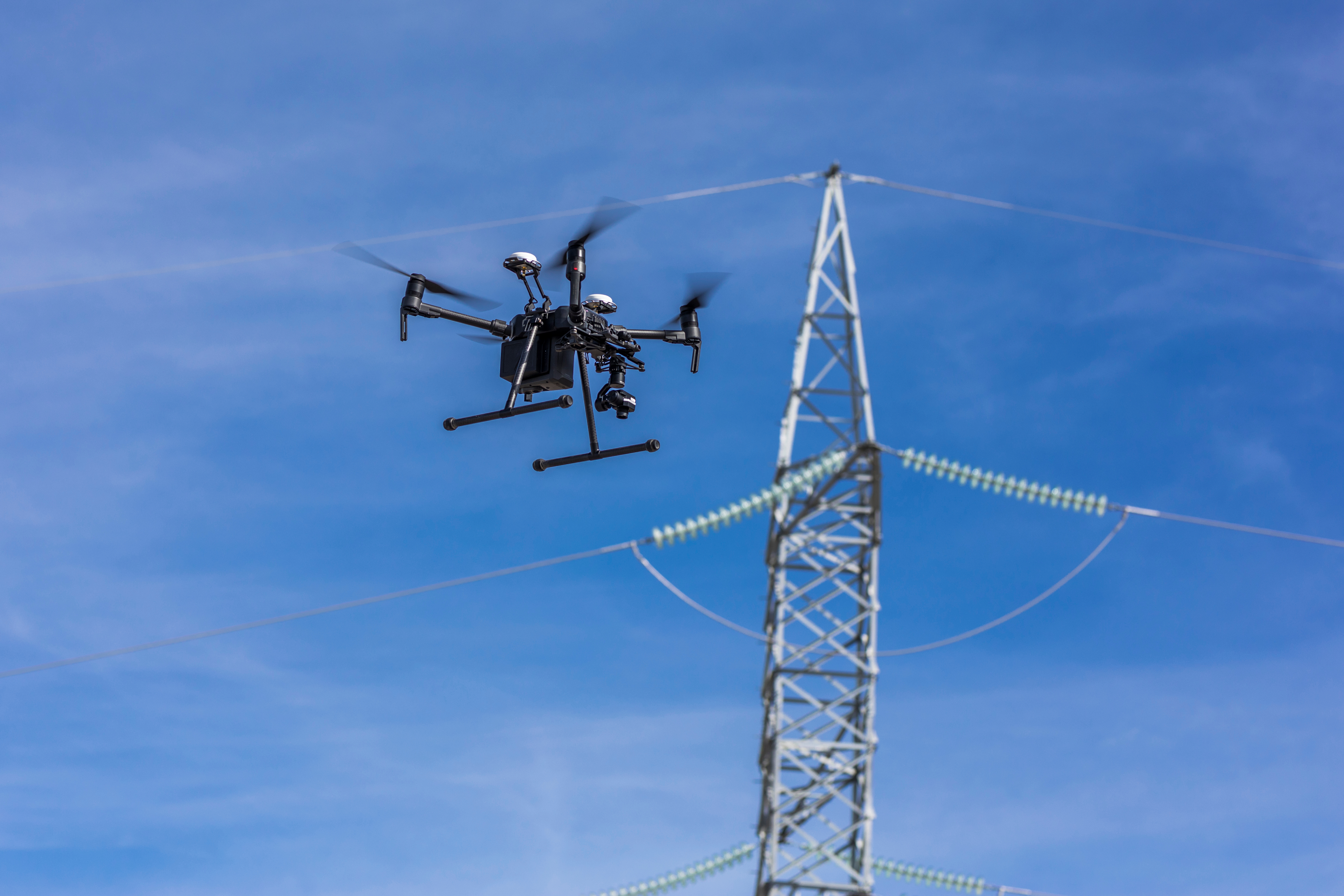 Picture of a drone flying in the sky inspecting powerlines