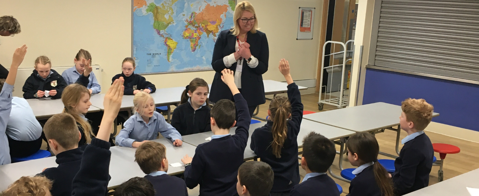 Image of students in classroom with their hands up